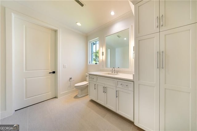 bathroom with toilet, tile patterned floors, crown molding, and vanity