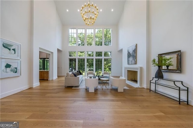 living room featuring a towering ceiling, light hardwood / wood-style floors, and a chandelier