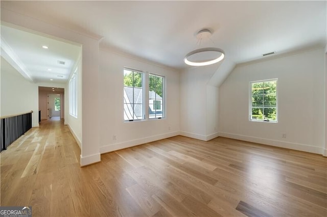 spare room with a wealth of natural light, crown molding, and light hardwood / wood-style flooring