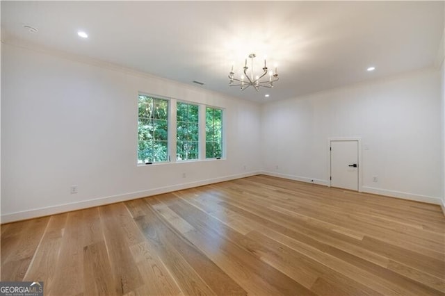 spare room featuring light wood-type flooring, crown molding, and a notable chandelier