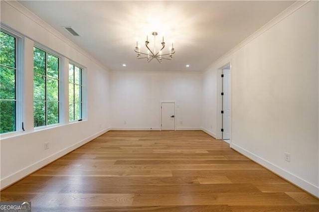 spare room with light wood-type flooring, an inviting chandelier, and ornamental molding