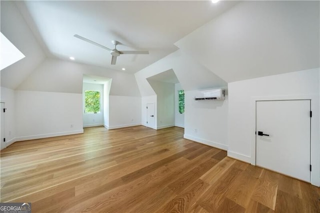 bonus room featuring vaulted ceiling, a wall unit AC, ceiling fan, and light hardwood / wood-style flooring