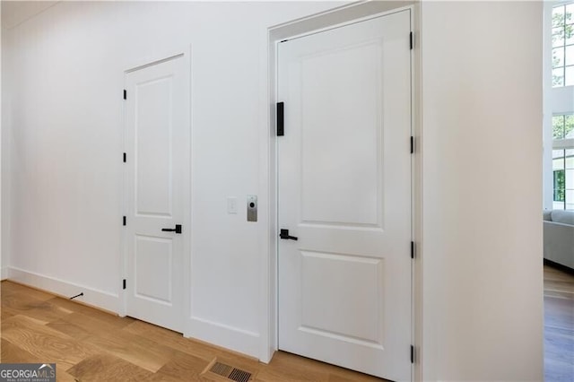 hall with light hardwood / wood-style floors and a wealth of natural light