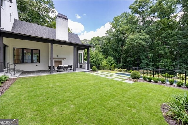 rear view of property featuring a patio, a yard, and a fenced in pool