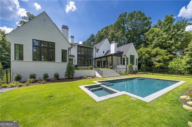 rear view of house with a pool with hot tub, a yard, and a sunroom