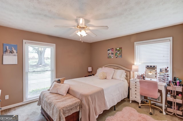 bedroom featuring ceiling fan, light colored carpet, and a textured ceiling