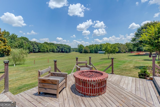 deck featuring an outdoor fire pit, a lawn, and a rural view