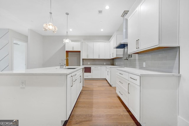 kitchen featuring sink, decorative backsplash, white cabinets, decorative light fixtures, and light wood-type flooring