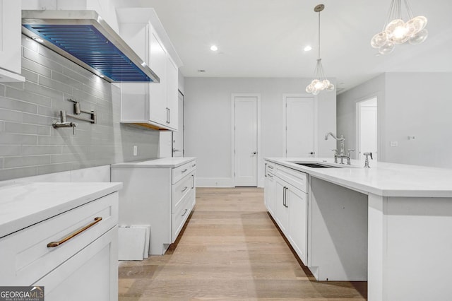 kitchen with ventilation hood, sink, white cabinets, and decorative light fixtures