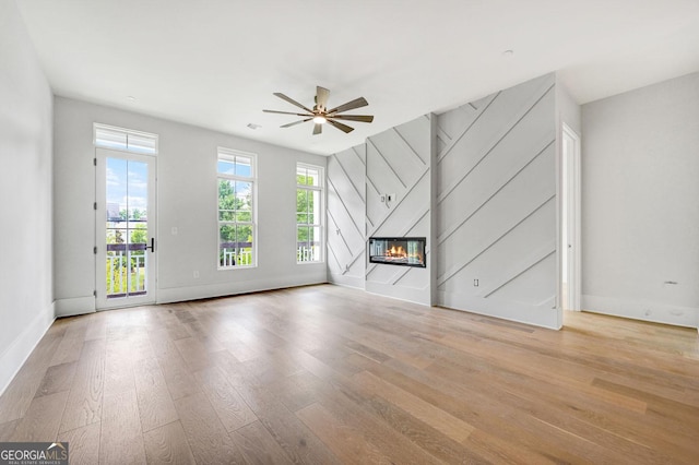 unfurnished living room featuring ceiling fan, a high end fireplace, and light hardwood / wood-style flooring