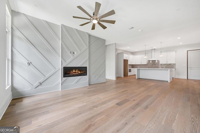 unfurnished living room featuring light hardwood / wood-style flooring and ceiling fan