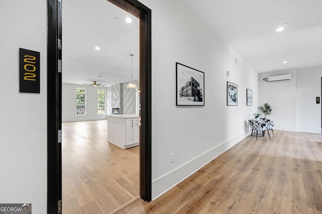 corridor with a wall mounted air conditioner and light hardwood / wood-style flooring