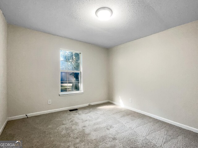 carpeted empty room with a textured ceiling