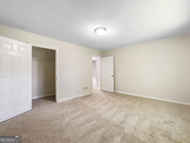 unfurnished bedroom with a textured ceiling, light colored carpet, and a closet