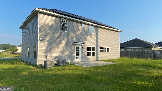 rear view of property with solar panels, central AC, a patio, and a yard