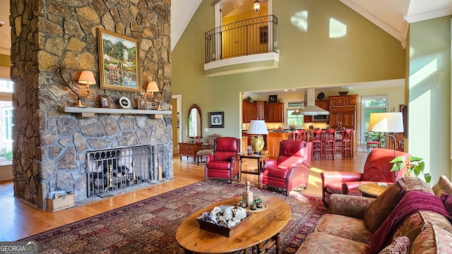 living room featuring light hardwood / wood-style flooring, high vaulted ceiling, a fireplace, and crown molding