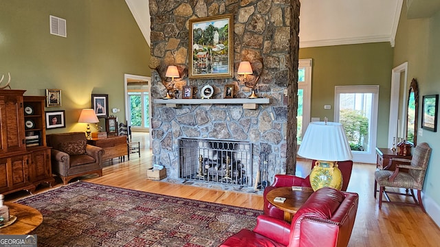 living room with high vaulted ceiling, crown molding, a fireplace, and wood-type flooring