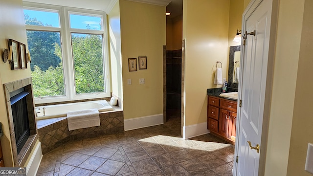 bathroom with vanity, tiled bath, crown molding, and a tiled fireplace