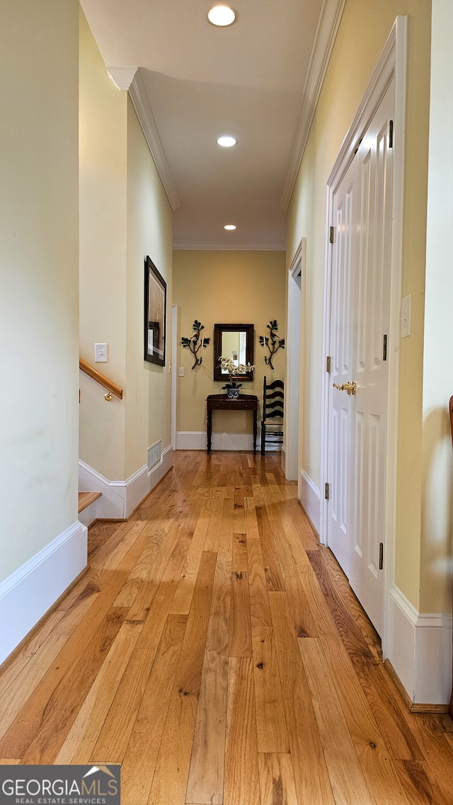 hall with ornamental molding and light wood-type flooring