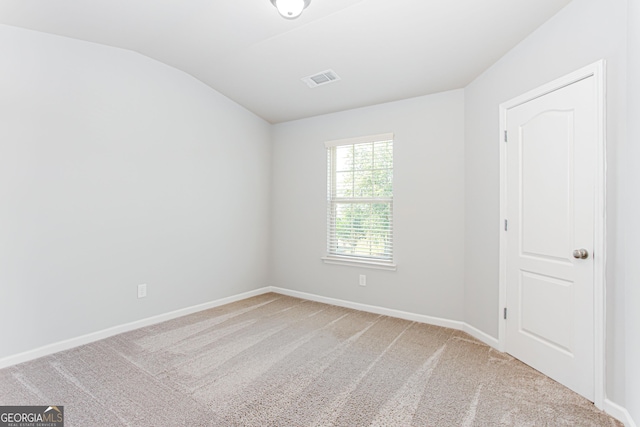 carpeted empty room with lofted ceiling