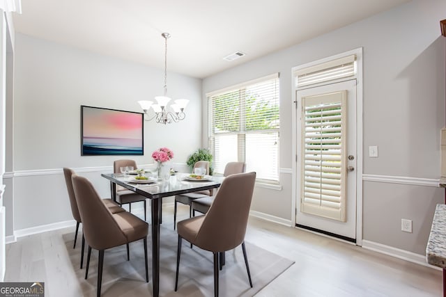 dining space with light hardwood / wood-style floors and a notable chandelier