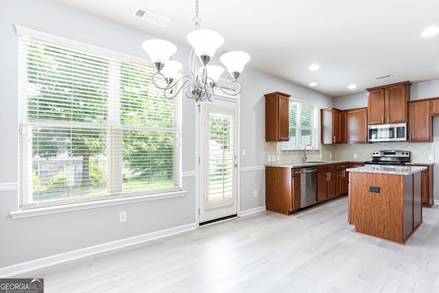 kitchen featuring stainless steel appliances, tasteful backsplash, a notable chandelier, pendant lighting, and a center island