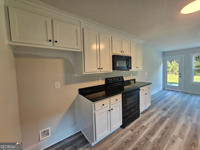 kitchen featuring white cabinets, light wood-type flooring, and black appliances