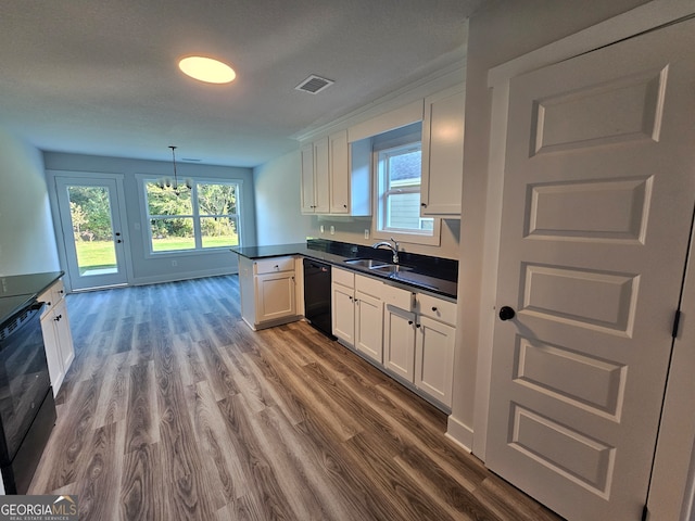 kitchen with hanging light fixtures, white cabinets, black dishwasher, hardwood / wood-style flooring, and sink