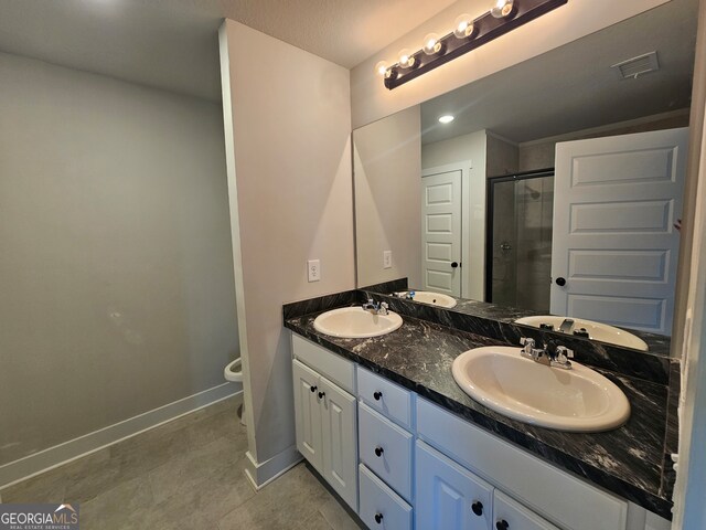 bathroom with vanity, toilet, tile patterned floors, and a shower with shower door