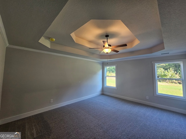 empty room featuring ceiling fan, a raised ceiling, crown molding, and carpet flooring