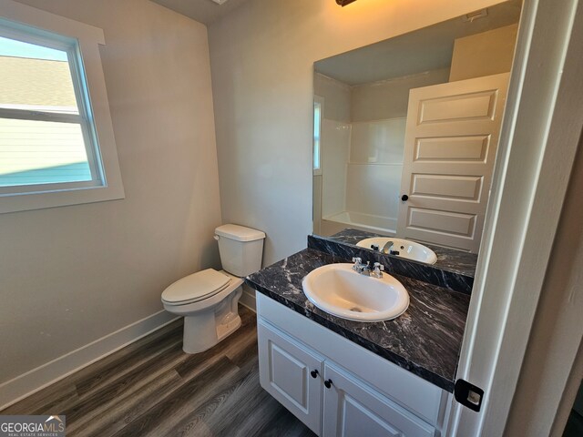 bathroom with wood-type flooring, vanity, a shower, and toilet