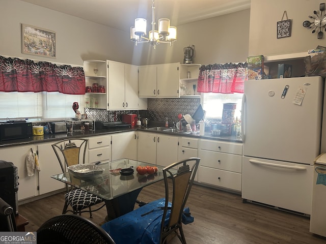 kitchen featuring decorative backsplash, a chandelier, white cabinetry, and white fridge