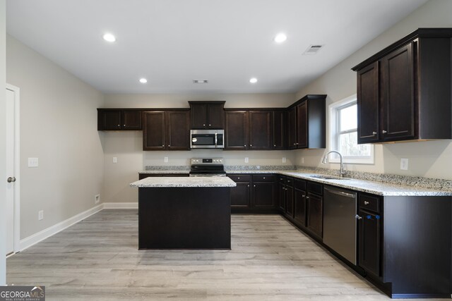 kitchen with sink, light hardwood / wood-style flooring, a kitchen island, and stainless steel appliances