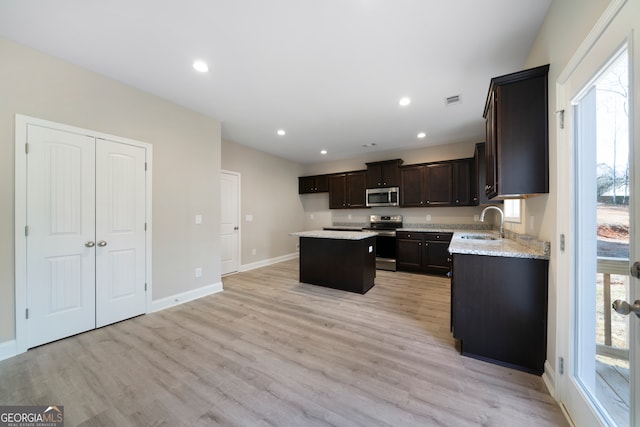 kitchen featuring stainless steel appliances, sink, light hardwood / wood-style floors, dark brown cabinetry, and a center island