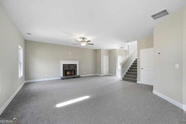 unfurnished living room featuring a stone fireplace and ceiling fan