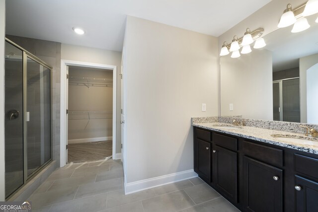 bathroom with tile patterned flooring, dual vanity, and a shower with door