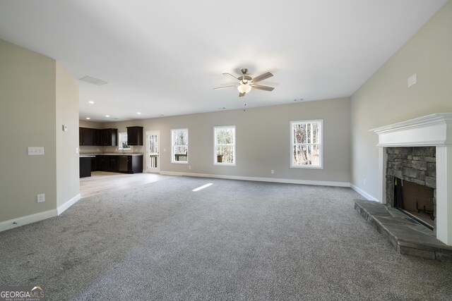 unfurnished living room featuring a fireplace, light carpet, and ceiling fan