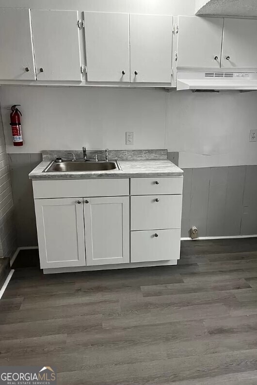 kitchen with dark wood-type flooring, white cabinetry, and sink