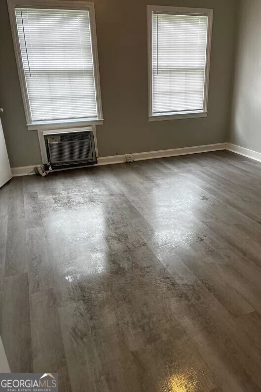 empty room with wood-type flooring and a wall mounted air conditioner