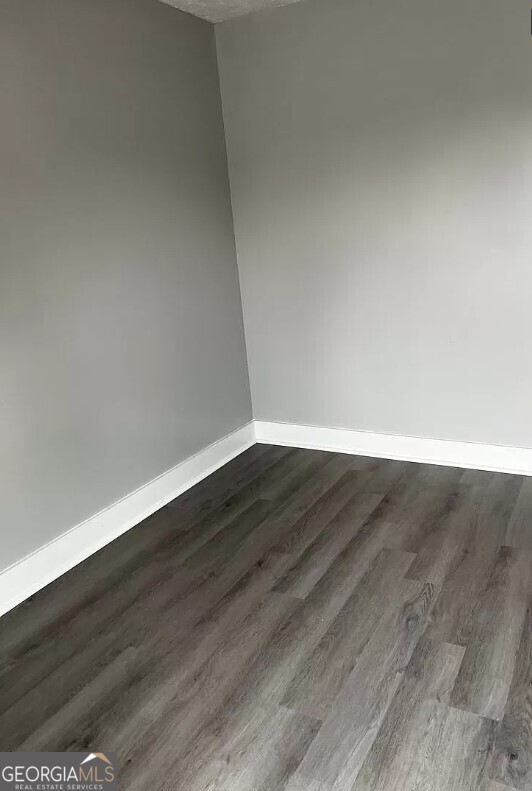 spare room with a textured ceiling and dark hardwood / wood-style flooring