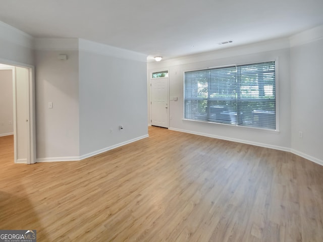 empty room with light hardwood / wood-style flooring and ornamental molding