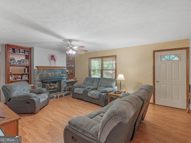 living room with light hardwood / wood-style flooring, a fireplace, and a textured ceiling