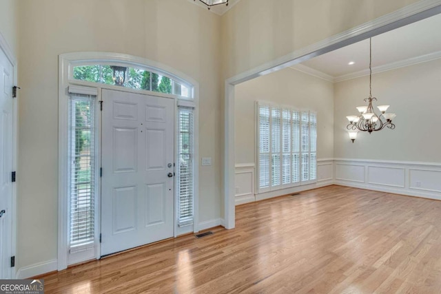 foyer with ornamental molding, hardwood / wood-style flooring, and a notable chandelier