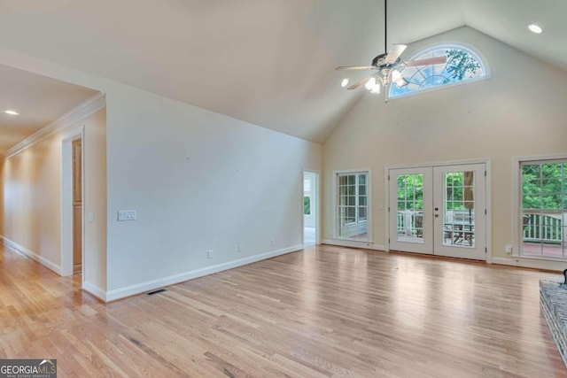 unfurnished living room featuring french doors, ceiling fan, a wealth of natural light, and light hardwood / wood-style flooring