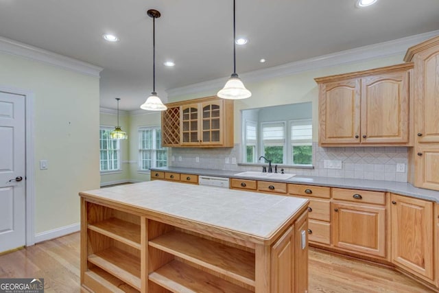 kitchen with a center island, ornamental molding, tile counters, and sink