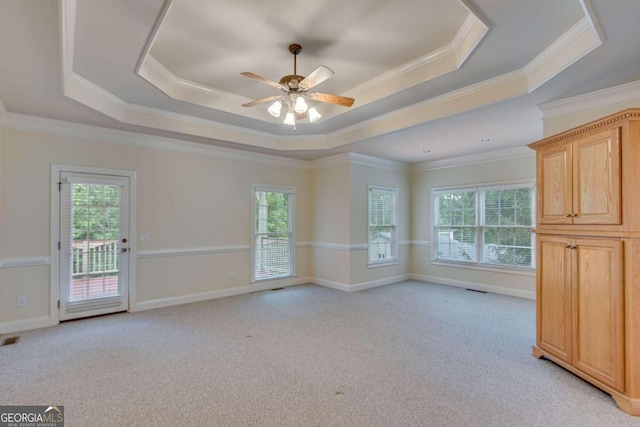 unfurnished room with ceiling fan, light carpet, ornamental molding, and a tray ceiling