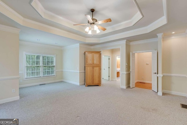 carpeted empty room featuring ceiling fan, crown molding, and a raised ceiling