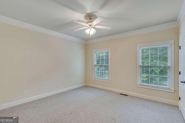 spare room featuring ceiling fan, light colored carpet, and crown molding