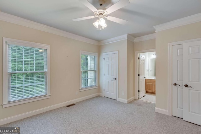 unfurnished bedroom featuring ensuite bathroom, light carpet, ceiling fan, and ornamental molding