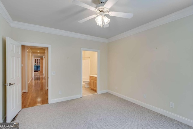 unfurnished bedroom featuring ensuite bath, light colored carpet, ceiling fan, and crown molding